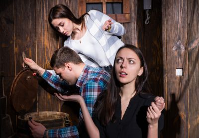 2 players of escape game searching in the barrel, 1 player looking around questioningly